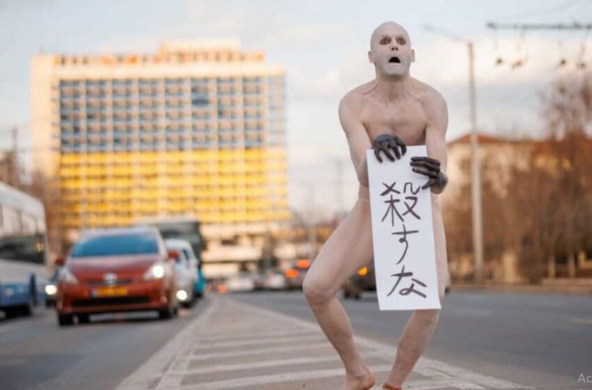  (foto) Arta nu are limite: Bărbatul gol, cu o pancartă în centru capitalei, a stârnit indignare pe internet